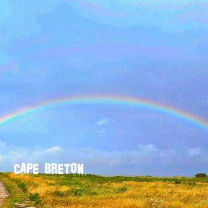 Vivid full rainbow over the Inverness boardwalk and town in Cape Breton, Nova Scotia, with bold CAPE BRETON lettering