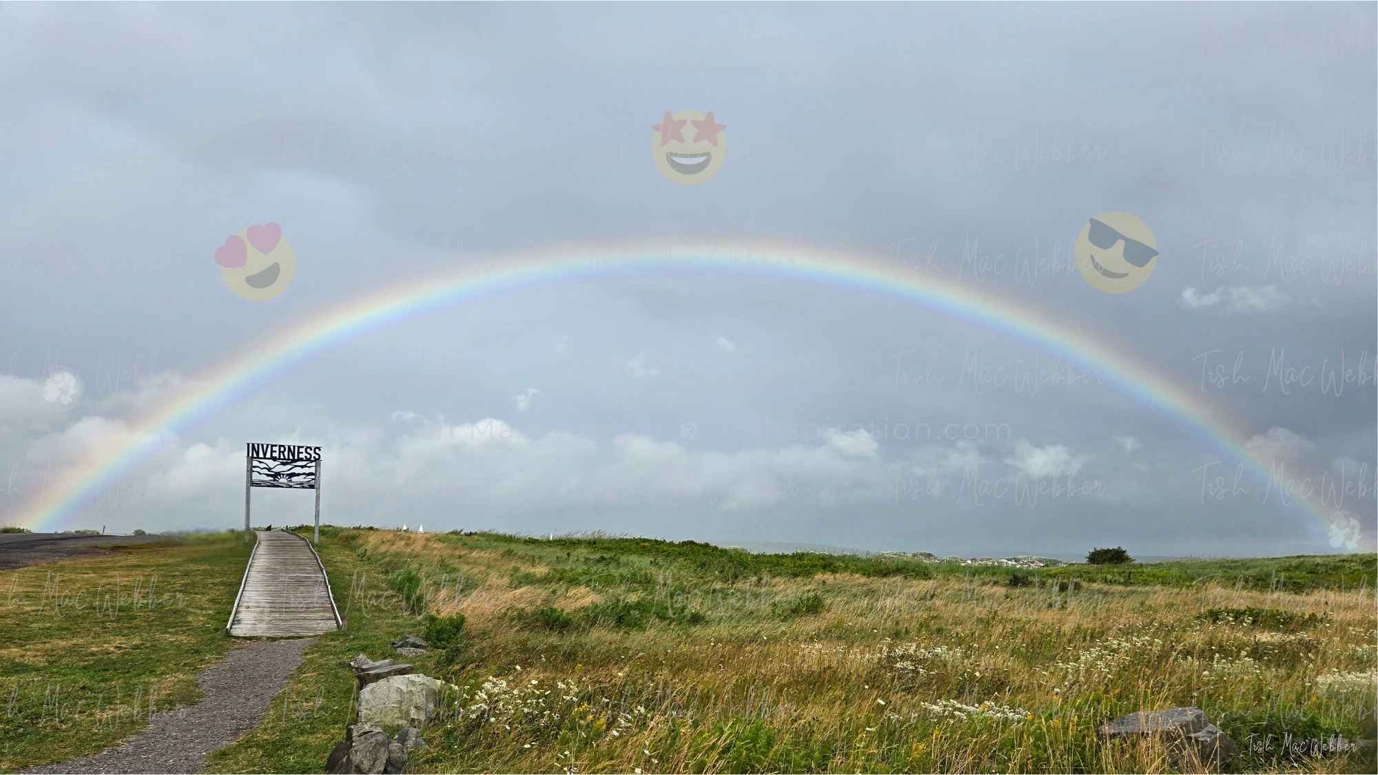 Full rainbow over the Inverness boardwalk and town with the Inverness sign and three smiling emojis with heart eyes, star eyes, and sunglasses floating over the rainbow.