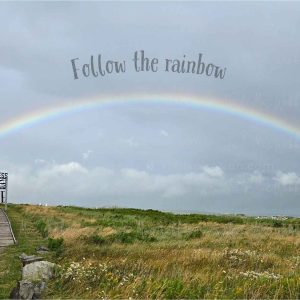 Full rainbow over the Inverness boardwalk and town with the Inverness sign and the words Follow the rainbow and HOME.