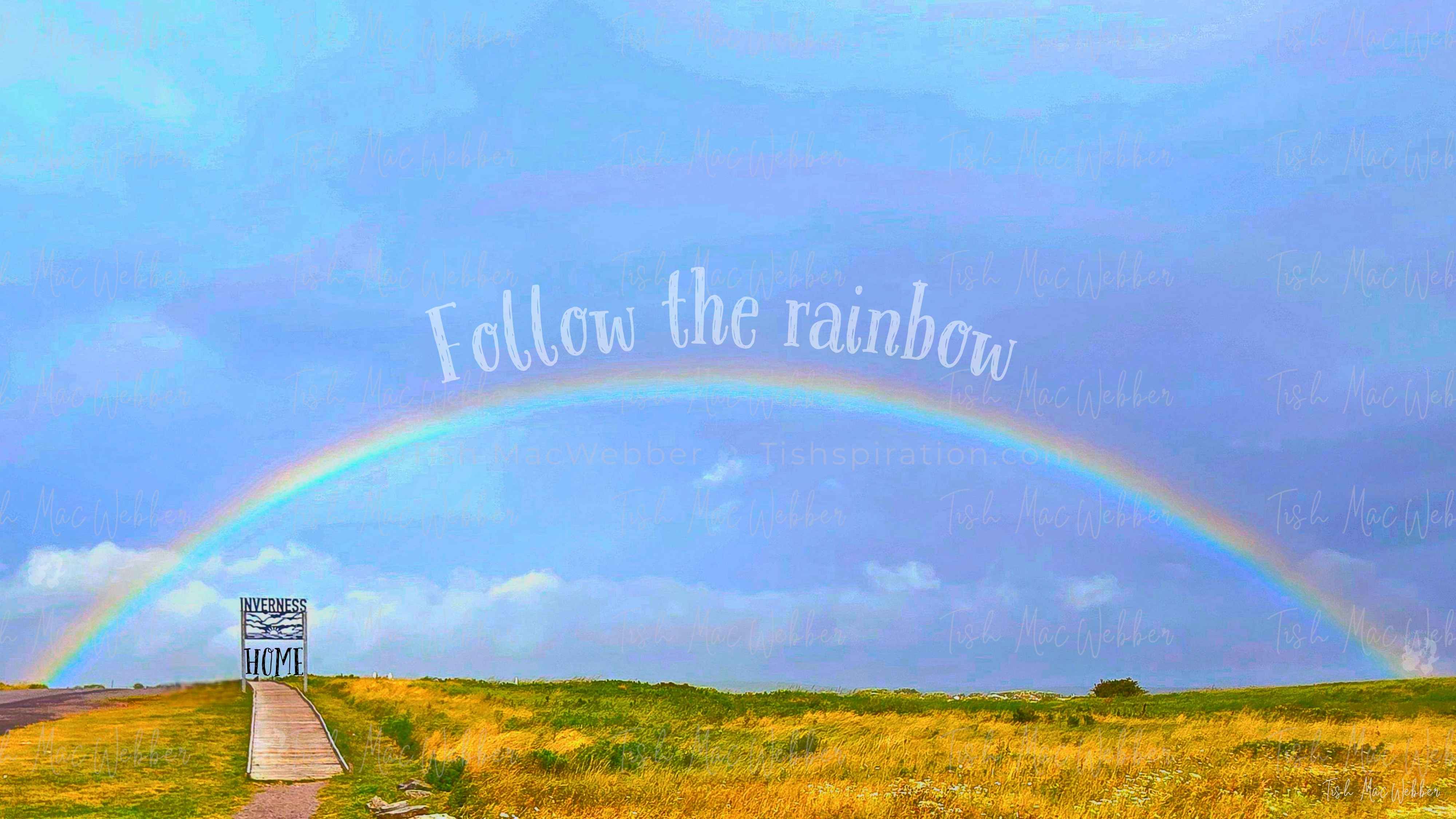 Vivid full rainbow over the Inverness boardwalk and town in Cape Breton, Nova Scotia, with the Inverness sign and the words Follow the rainbow and HOME