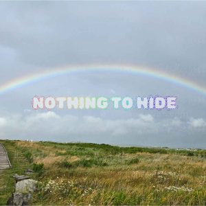 Full rainbow over the Inverness boardwalk and town in Cape Breton, Nova Scotia, with rainbow-coloured NOTHING TO HIDE lettering