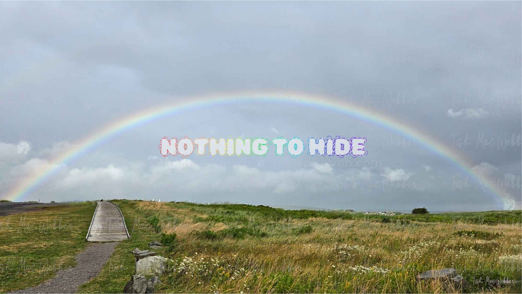 Full rainbow over the Inverness boardwalk and town in Cape Breton, Nova Scotia, with rainbow-coloured NOTHING TO HIDE lettering
