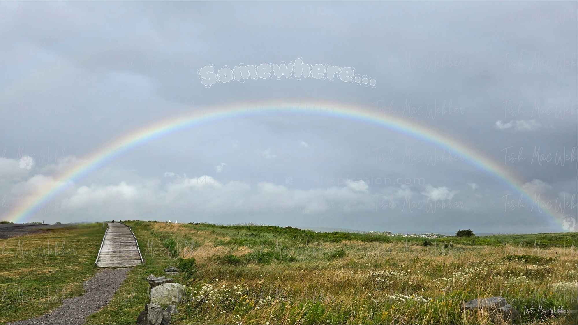 Full rainbow over the Inverness boardwalk and town in Cape Breton, Nova Scotia, with the word Somewhere above the rainbow
