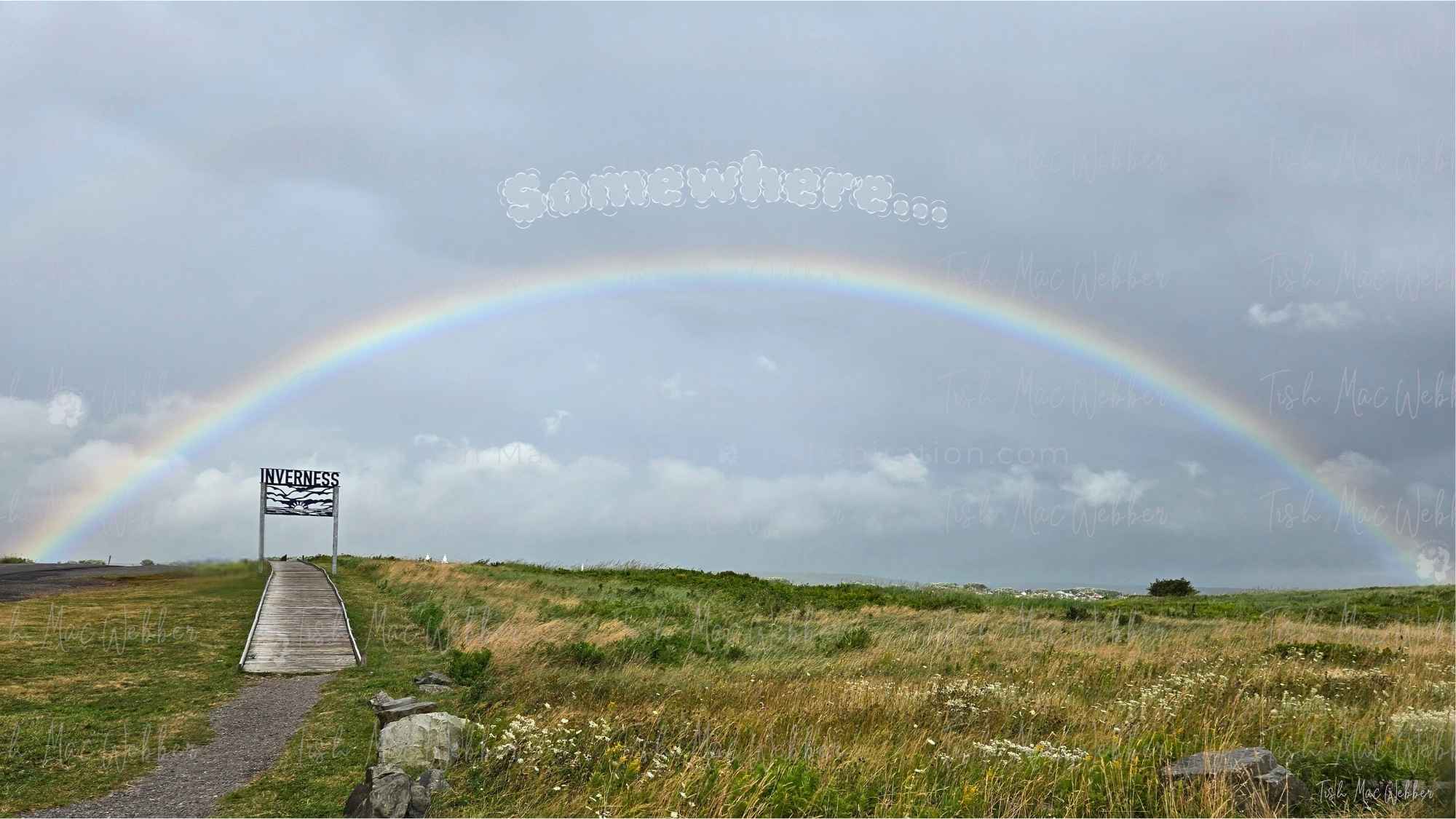 Full rainbow over the Inverness boardwalk and town with the Inverness sign and the word Somewhere above the rainbow