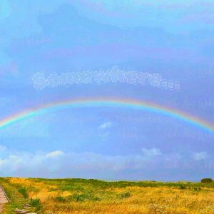 Vivid full rainbow over the Inverness boardwalk and town in Cape Breton, Nova Scotia, with the word Somewhere above the rainbow