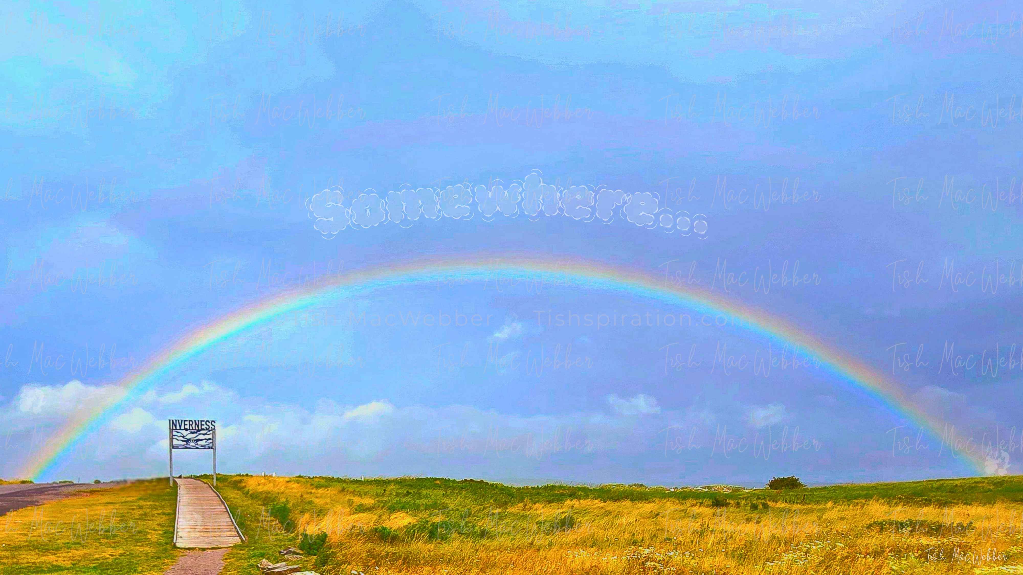 Vivid full rainbow over the Inverness boardwalk and town in Cape Breton, Nova Scotia, with the Inverness sign and the word Somewhere above the rainbow